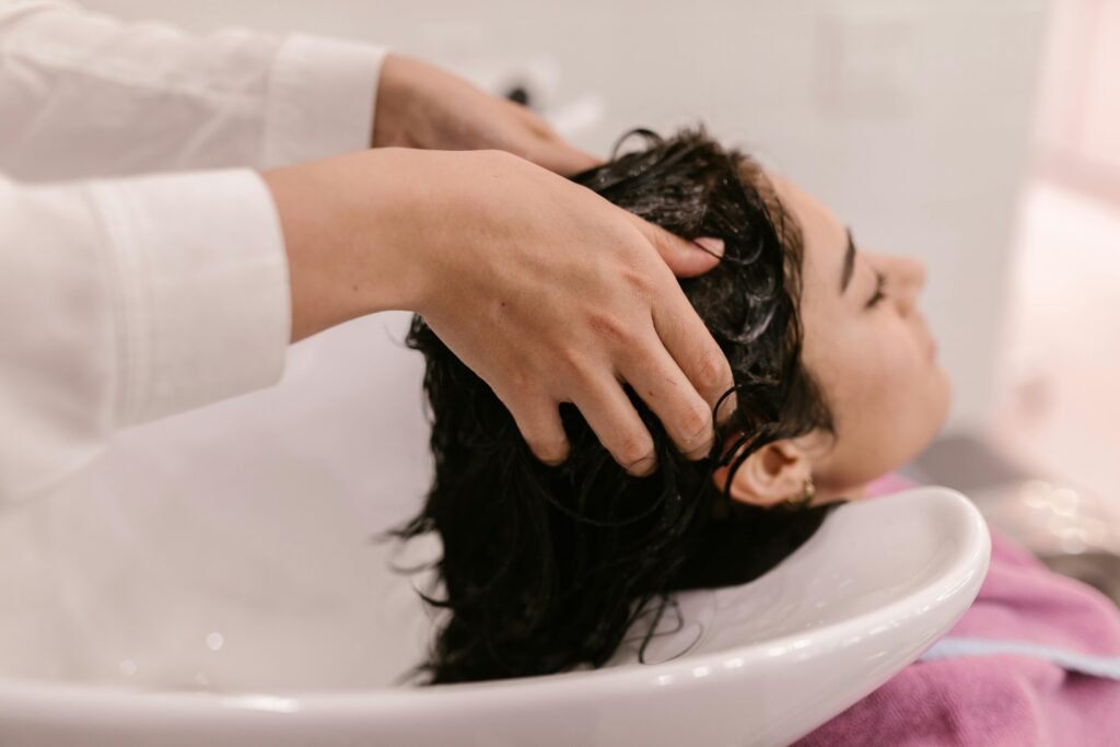 How Often Hair Wash: Tips For All Hair Types 1 A woman enjoys a relaxing hair wash at a salon. Captured in a cozy indoor setting.